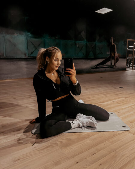 Woman in black taking a mirror selfie at the gym