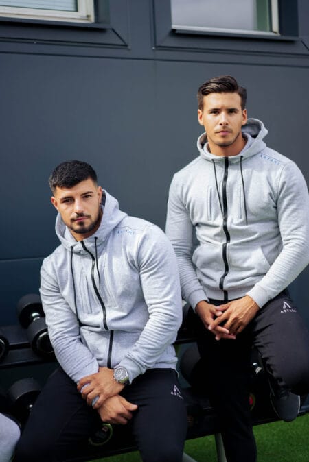 Two men in gray zip hoodies at the gym