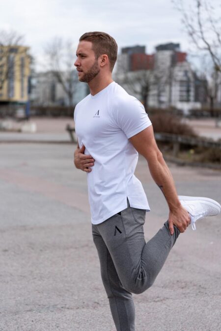 Man in a white T-shirt stretching outdoors